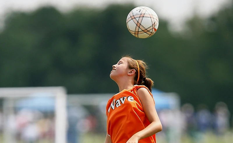 A teenage girl heading a football