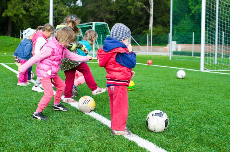 Young children kicking footballs towards a goal